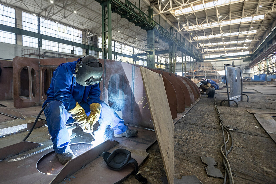 Welder working on a steel structure in a shipbuilding environment